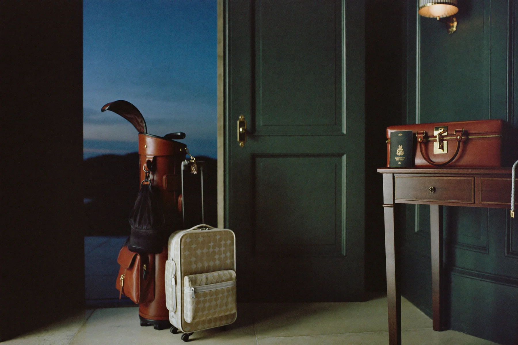 A leather golf bag ready for a trip beside a forest-green panelled door