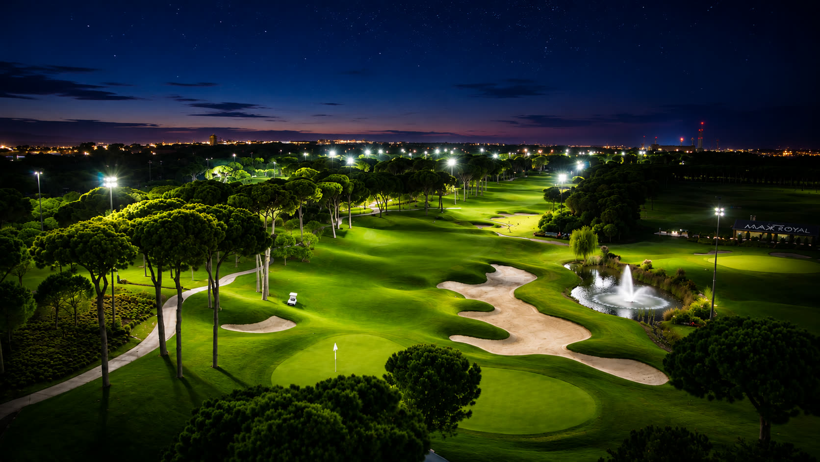 Floodlit championship green surrounded by pines at night in Belek